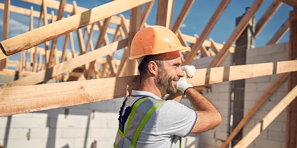 Man in hard hat carrying roof truss